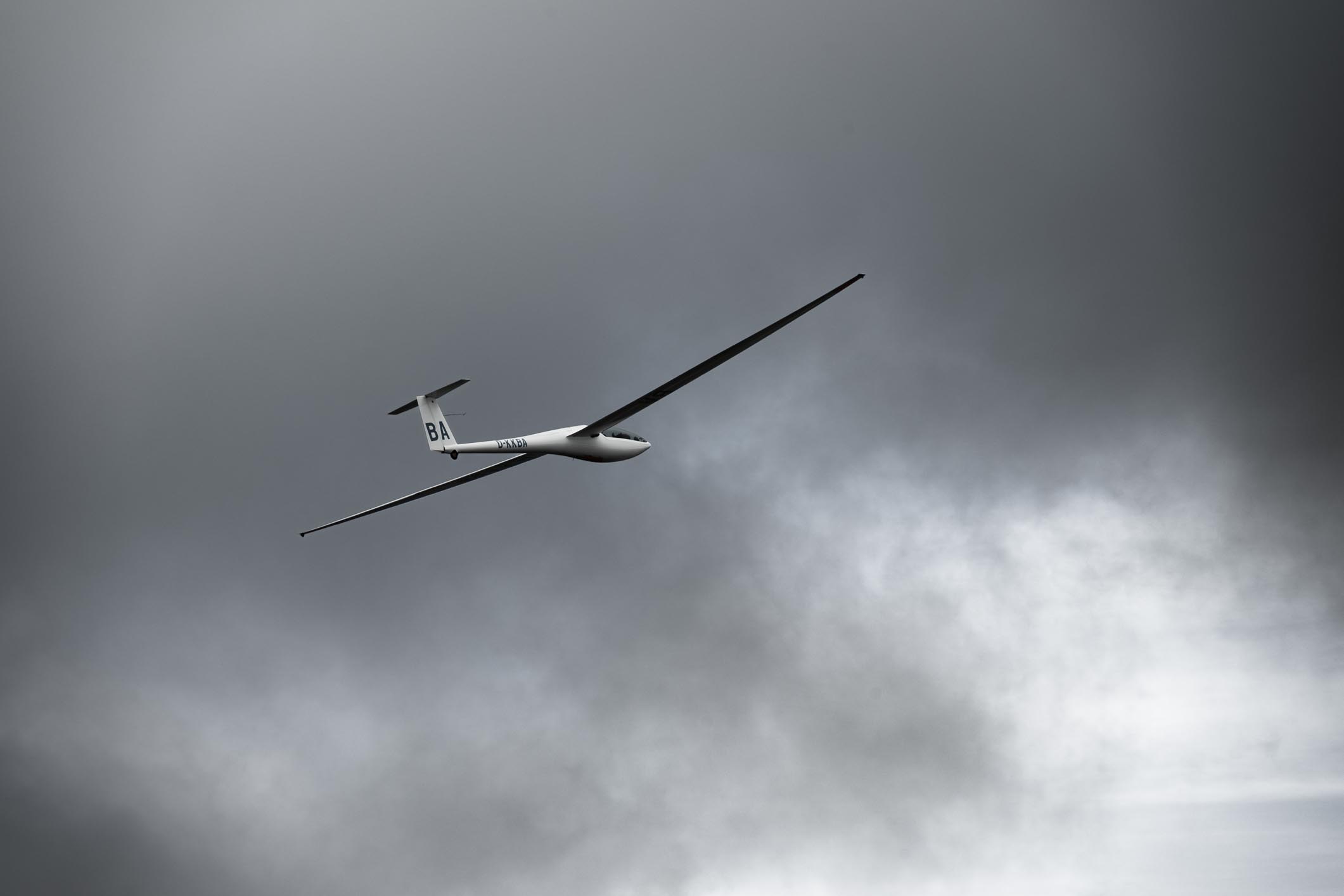 Ein Segelflugzeug im Kurvenflug unter bewölktem Himmel.